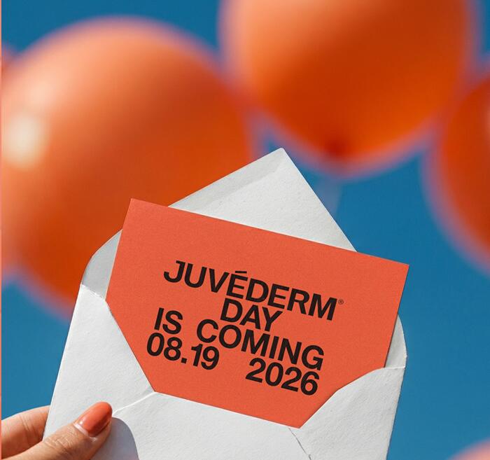 Hand holding a white envelope with a red 'Juvéderm Day is coming 08.19.2026' invitation card against a backdrop of orange balloons